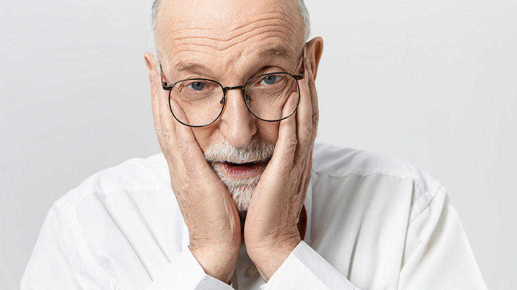 Portrait of emotional desperate elderly man with beard and bald head holding hands on his face, falling into panic because he forgot to take his medicine, having frustrated fearful facial expression