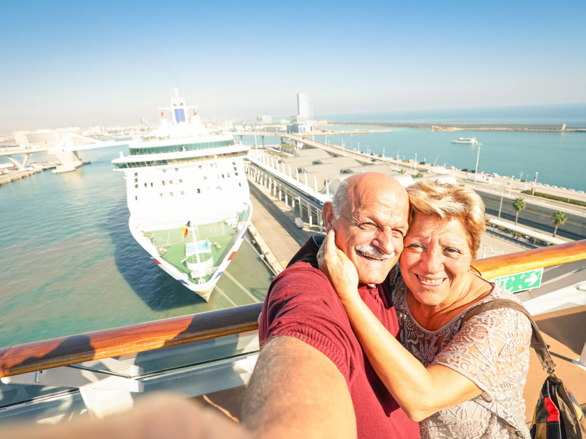 Senior happy couple taking selfie on ship at Barcelona harbour background - Mediterranean cruise travel tour - Active elderly concept with retired people around the world - Warm afternoon color tones