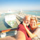 Senior happy couple taking selfie on ship at Barcelona harbour background - Mediterranean cruise travel tour - Active elderly concept with retired people around the world - Warm afternoon color tones