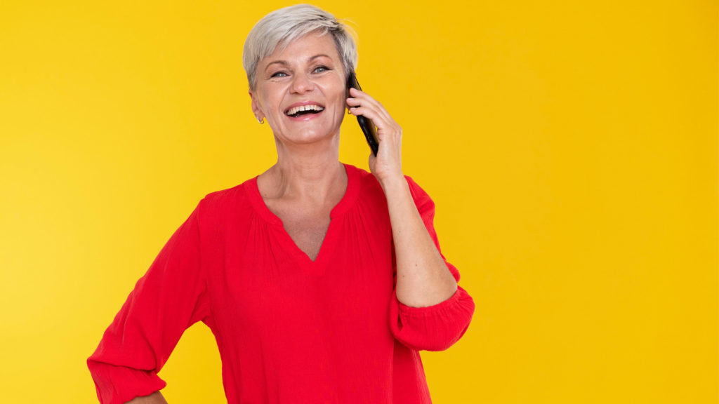 Woman on the phone smiling because she understands how to apply for Medicare online.