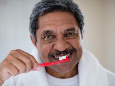 Portrait of senior man brushing teeth in bathroom at home