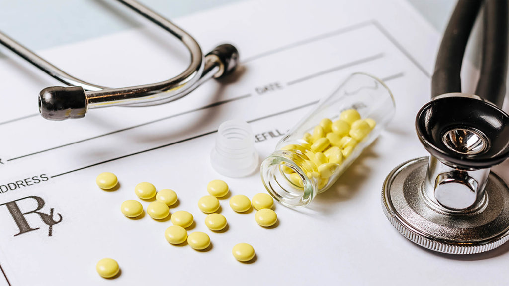 Medical concept. Yellow pills with stethoscope, pills, notepad, medical prescription on the doctor's desktop. Treating a patient in a hospital with medication.
