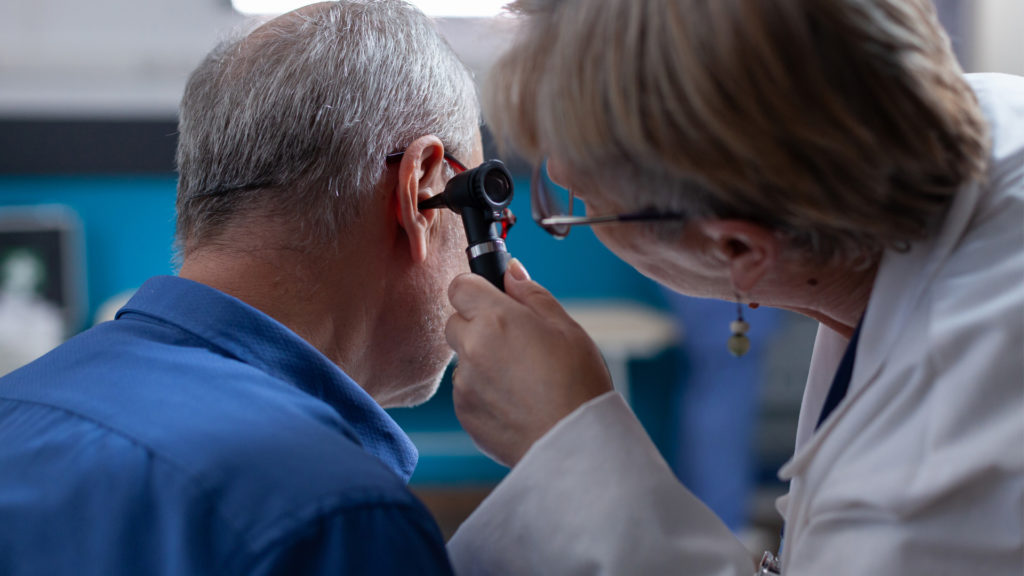 Image of senior getting his ear looked at by his new doctor after changing doctors.