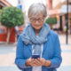 Older woman in glasses searching her phone for "Does Medicare Cover Vision?"