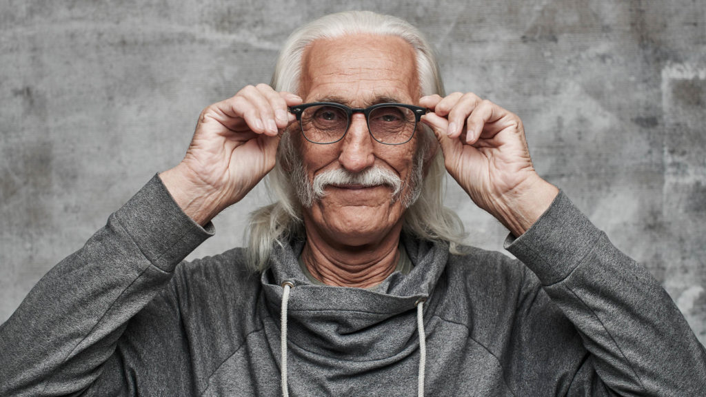 Older man putting glasses on his face wonders, does Medicare cover vision?