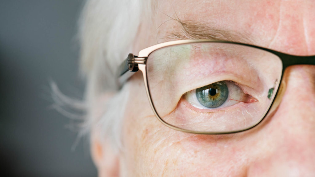 Close up of older woman's eye and glasses as she wonders does Medicare cover vision care?